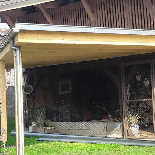 Carport triangulaire adossé à une grange du Sundgau
