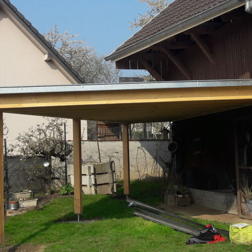 Carport triangulaire adossé à une grange du Sundgau